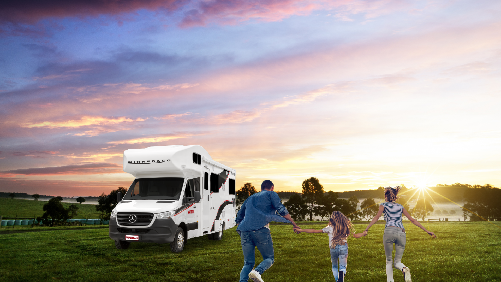 motorhome parked on a grass field during sunset with three people running towards it